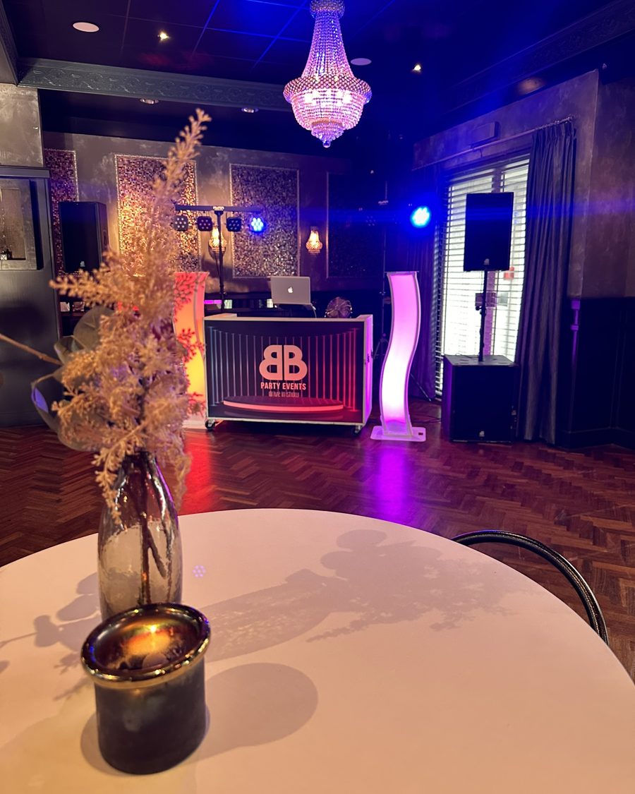 DJ-booth met kroonluchter en paarse lichtpilaren