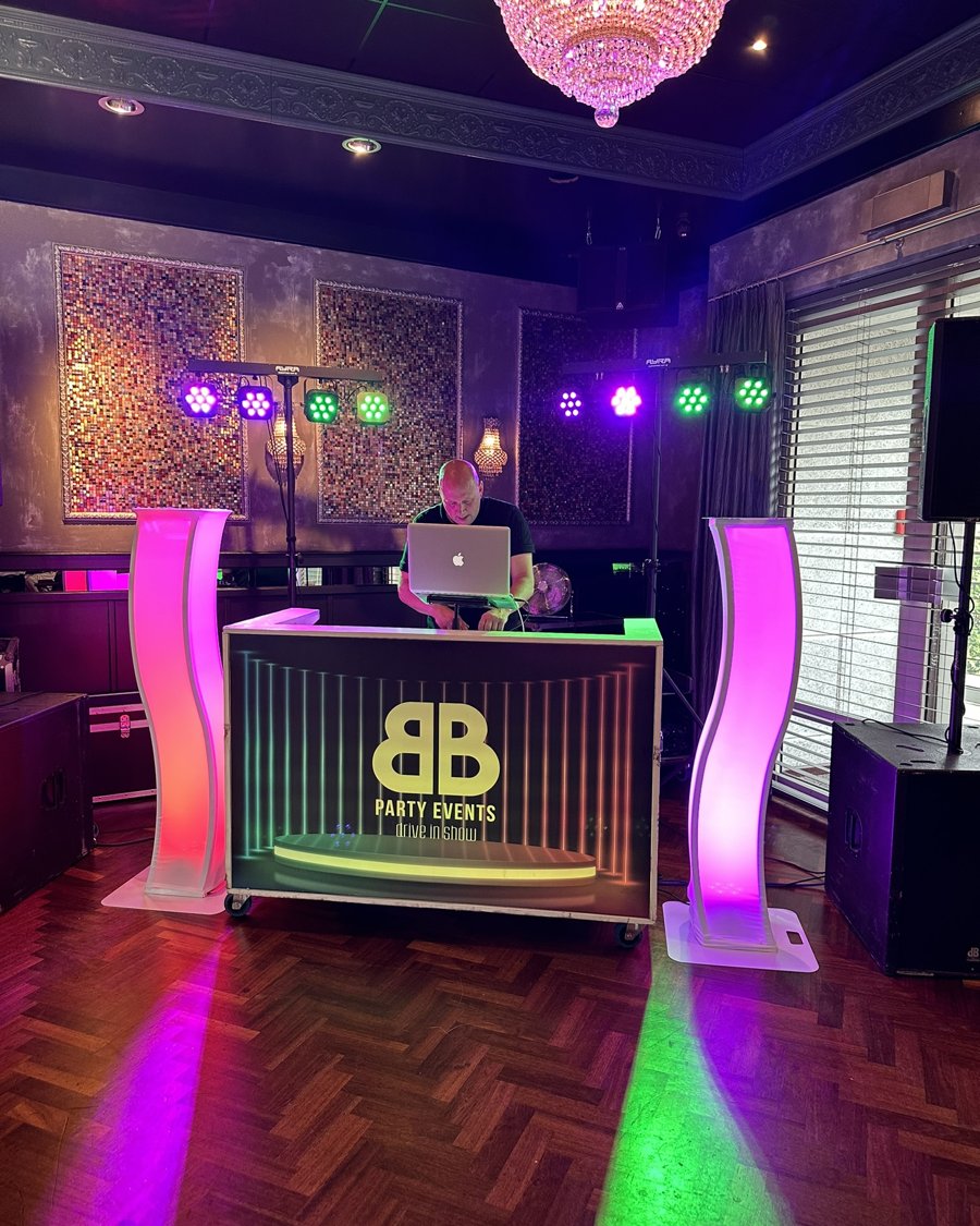 DJ-booth met kroonluchter en roze lichtpilaren
